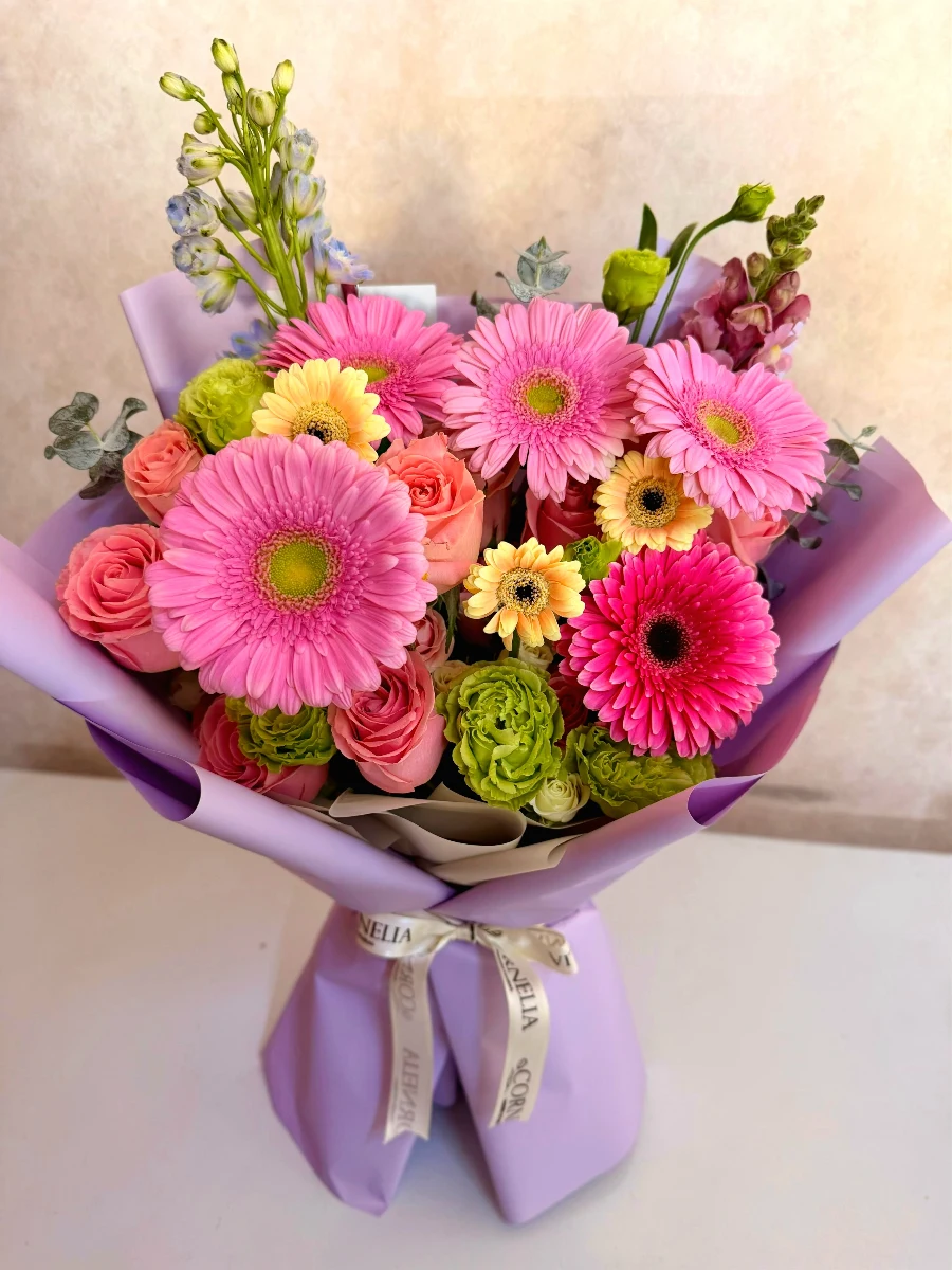 Manos de florista atando un listón negro a un ramo blush